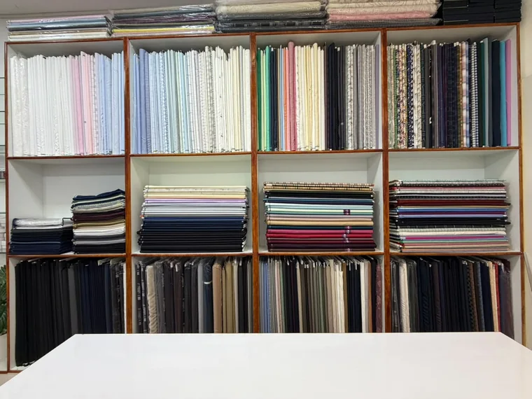 Shelves of folded suiting and shirting fabric in the Arsu store