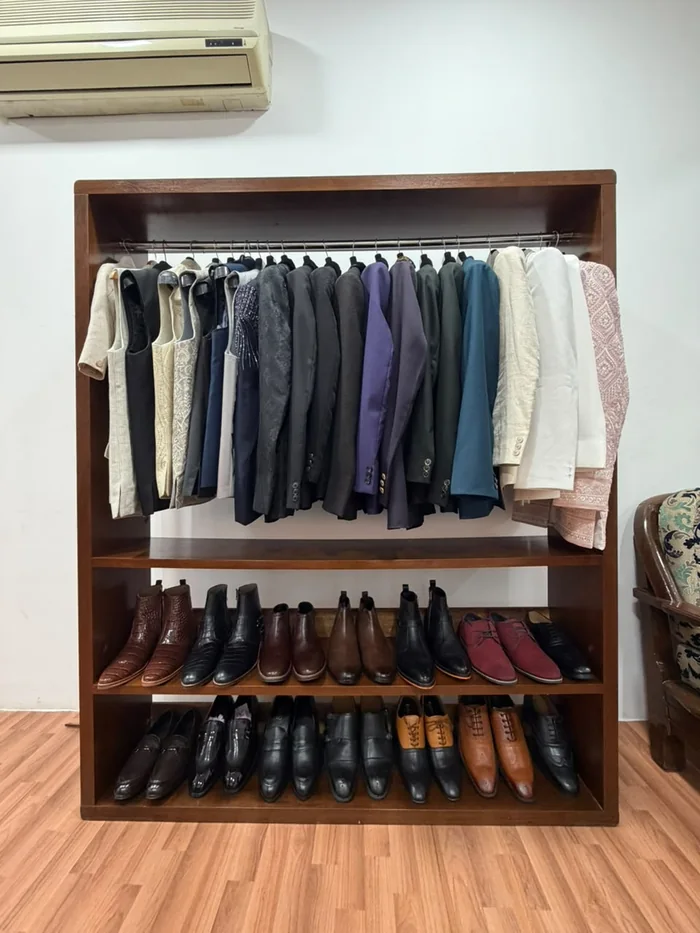 A rail of finished jackets above a row of formal shoes